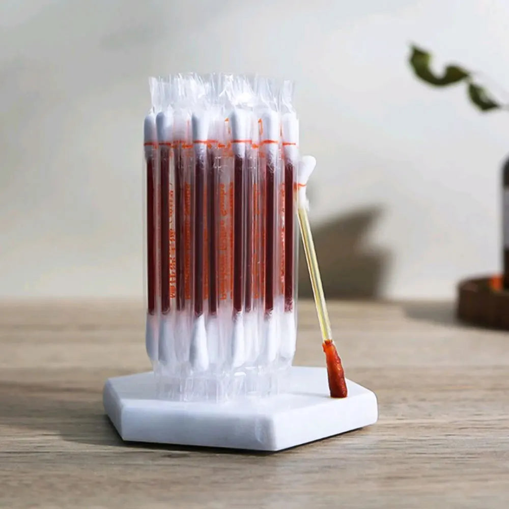 A set of disposable medical iodine cotton swabs in clear plastic tubes standing upright on a white base.