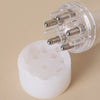 A clear glass bottle with a silicone applicator comb and roller balls for applying serums or oils.