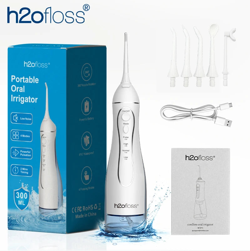 A white portable oral irrigator device is shown next to its packaging and accessories on a reflective surface.