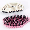 A pink silicone styling comb with black bristles is shown next to a white spiral comb.