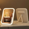 A modern LED vanity makeup mirror with a white frame and adjustable light is displayed on a countertop.