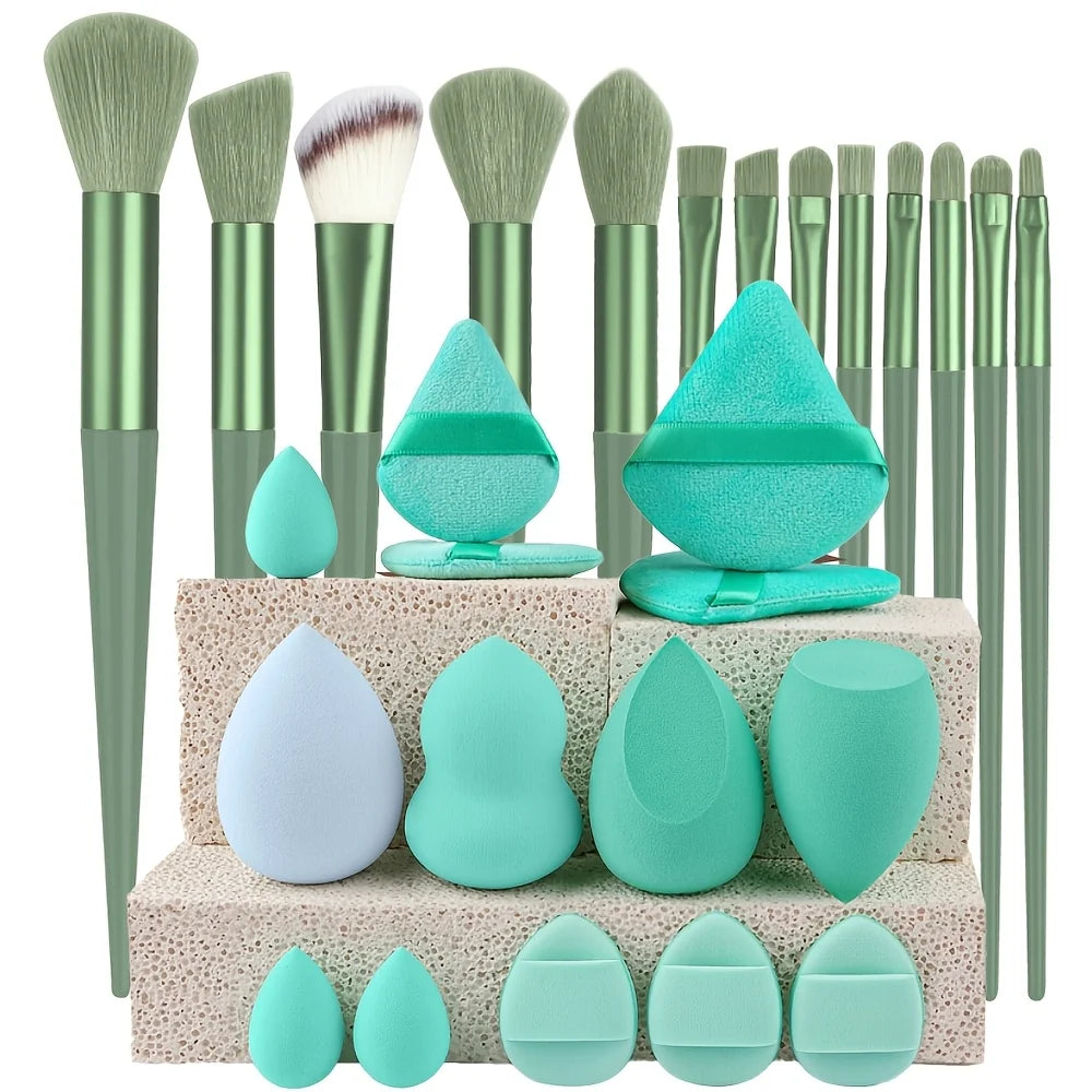 A complete makeup brush set featuring various sizes of green and teal synthetic brushes and sponges.