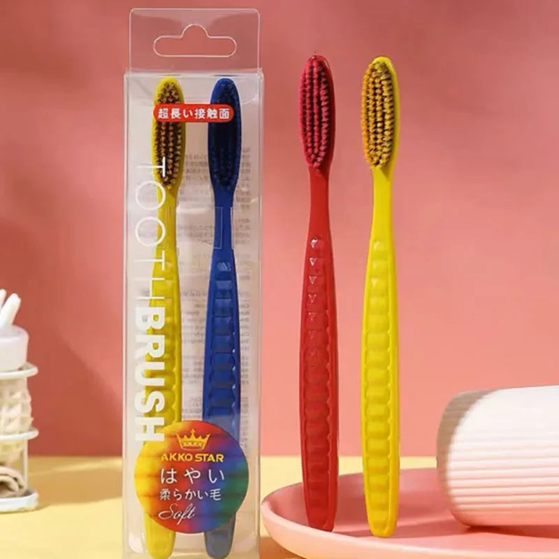 Un set de trois brosses à dents à poils souples jaunes, bleues et rouges, emballées dans un contenant en plastique transparen