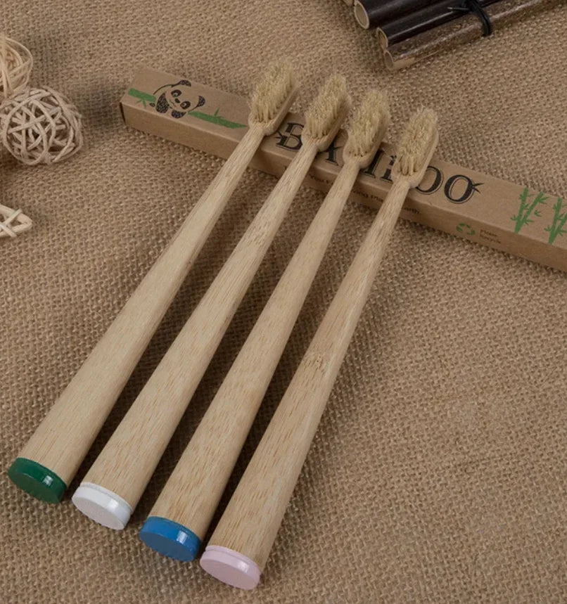 A set of ten natural bamboo toothbrushes lying on a beige fabric next to a wooden box.