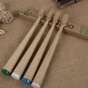 A set of ten natural bamboo toothbrushes lying on a beige fabric next to a wooden box.