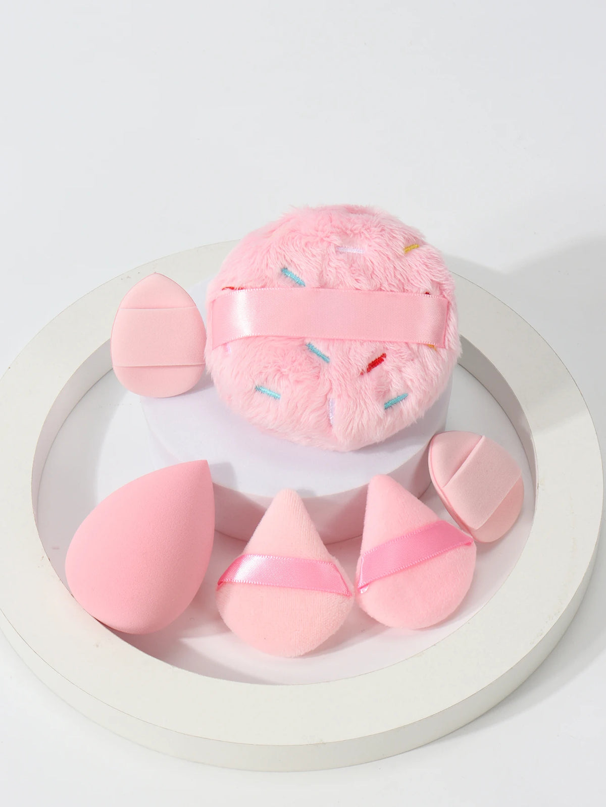 Un ensemble de poudres légères roses avec des bandes roses et des broderies colorées, présentées sur une assiette blanche.
