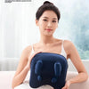A woman is using a dark blue electric massage pillow on her shoulder and neck.