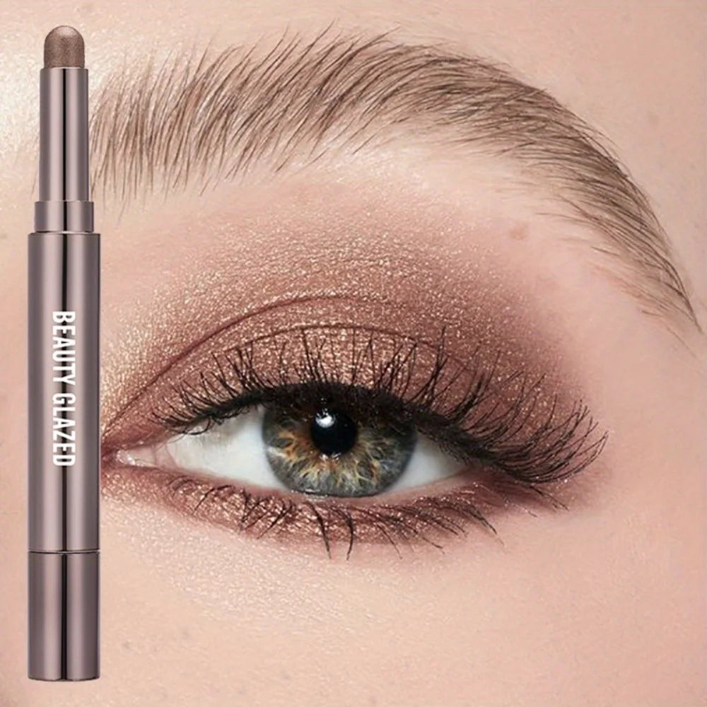 A cosmetic eyeshadow stick in a bronze shade is shown applied to an eye, demonstrating its texture and finish.