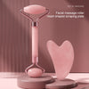A pink heart-shaped facial massage roller set featuring a long metal handle and a separate heart-shaped scraping plate.