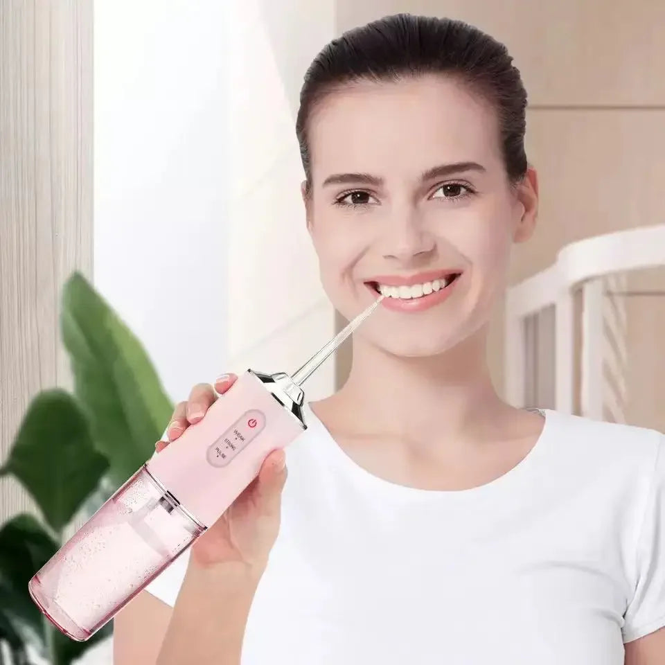 A woman is smiling while holding a pink 3-mode rechargeable oral irrigator water flosser device.