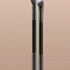 A pair of black makeup brushes with silver bristles displayed against a beige background.