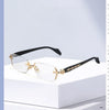 Pair of gold-rimmed retro frameless reading glasses with black arms displayed on a white surface.