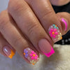 A close-up of a hand displaying colorful press-on acrylic flower nails with pink and orange accents.