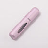 A pink portable refillable perfume bottle with a silver band, shown in a diagonal view.