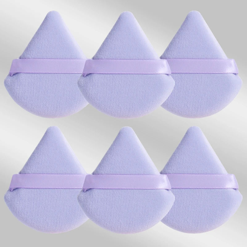 Un set de six éponges de maquillage triangulaires lavande avec des élastiques roses.