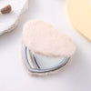 A heart-shaped foldable travel makeup mirror covered in soft pink faux fur resting on a white surface.