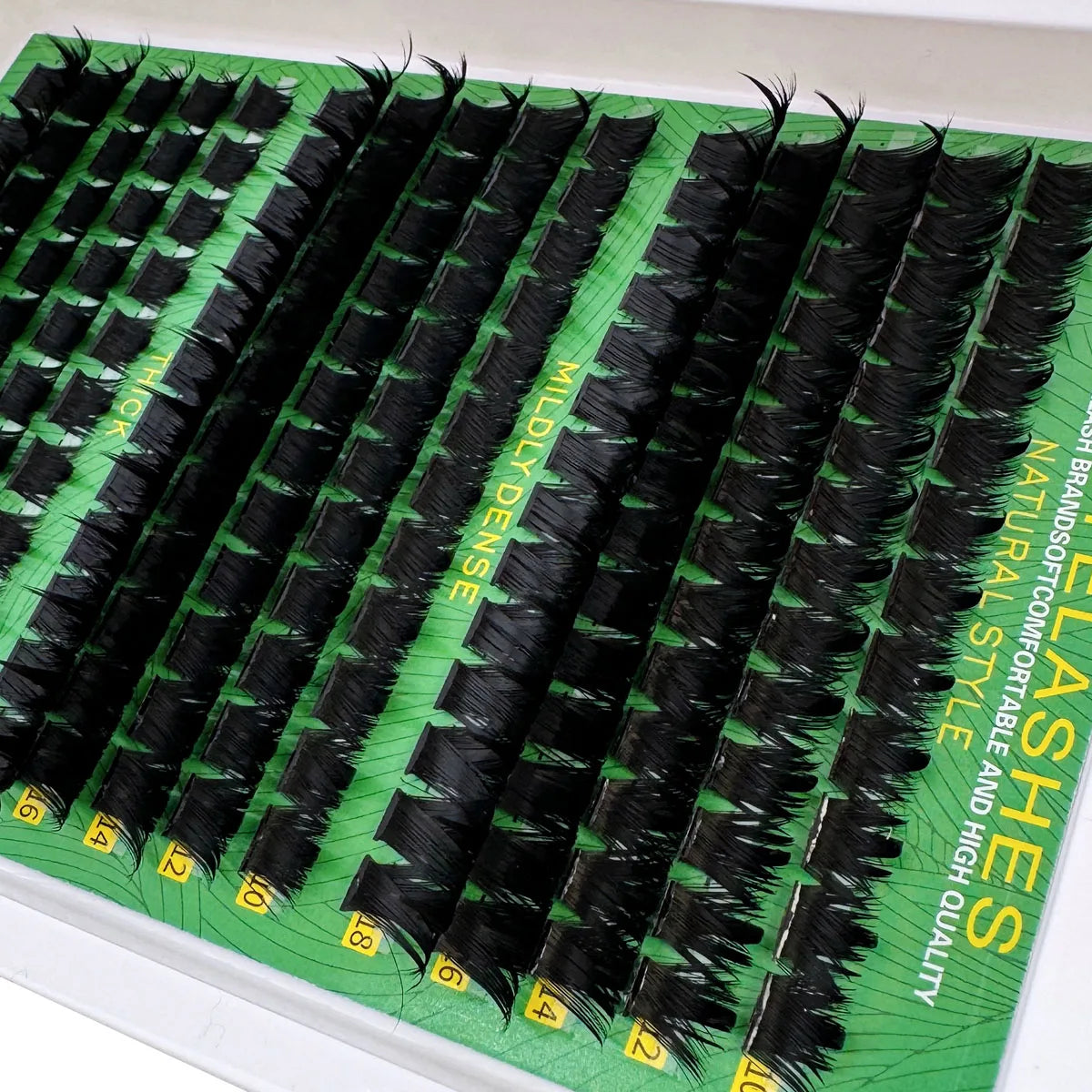 A display of black thick spiky cluster eyelash extensions packaged in green boxes.