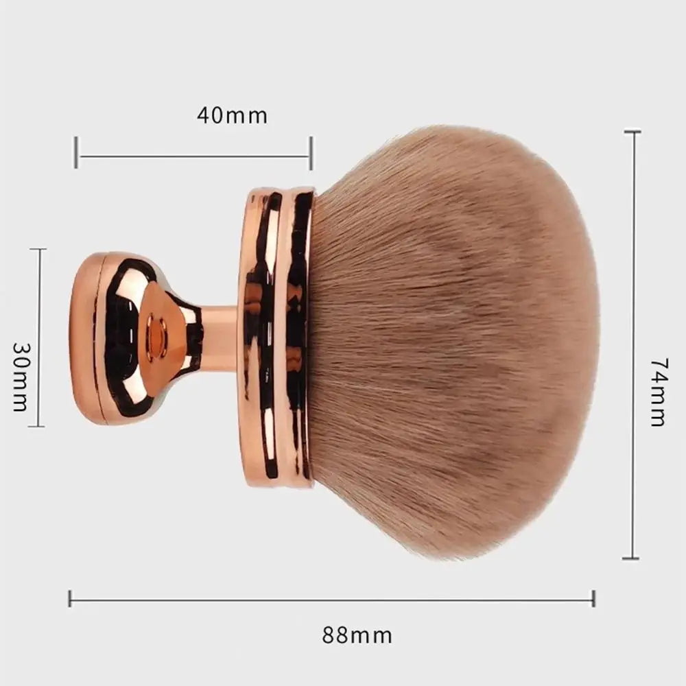 A large, round makeup brush with a gold-toned handle and a fluffy, light beige synthetic hair bristles.