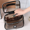 A hand opens a clear cosmetic bag with a zipper to reveal a brown mesh pouch inside.
