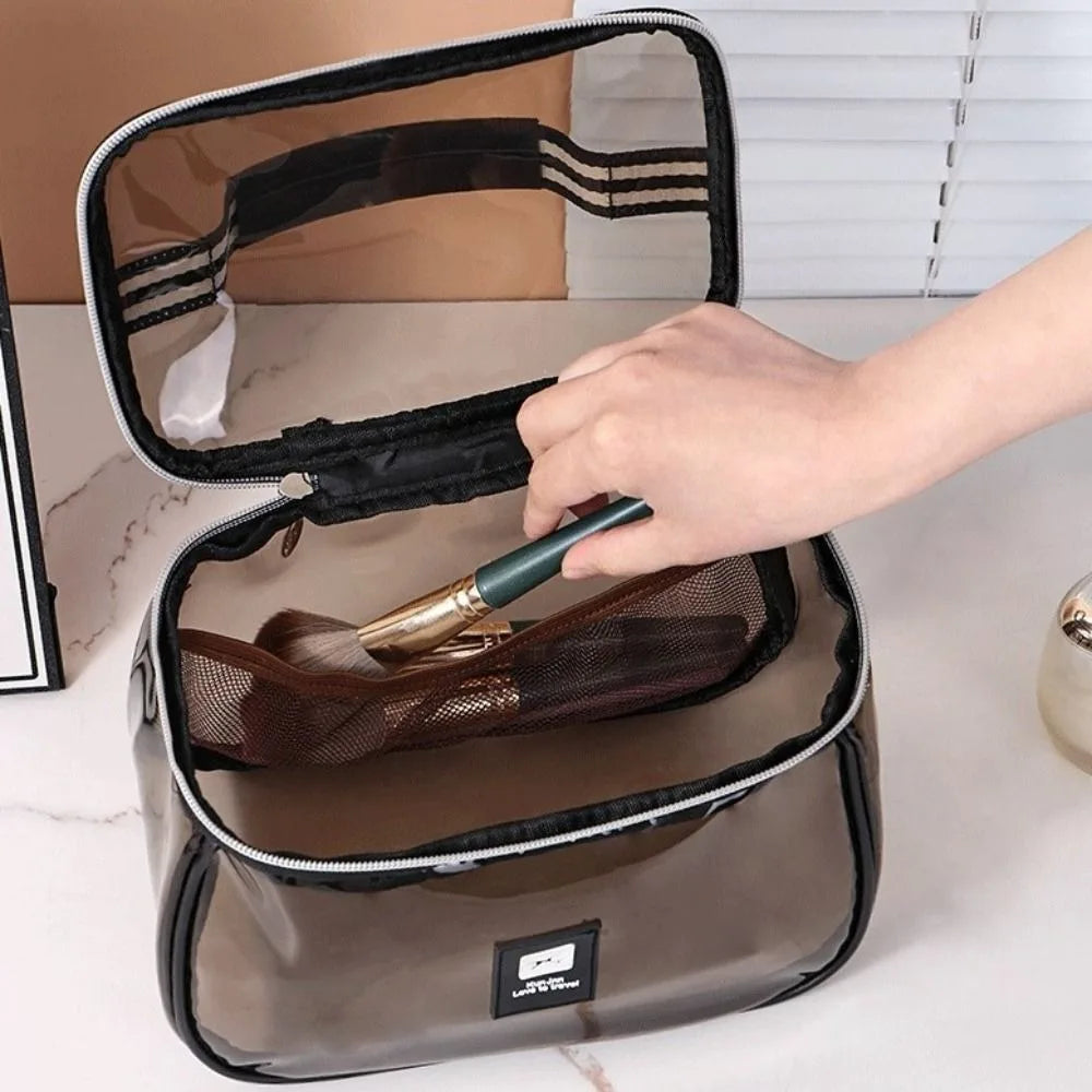 A hand opens a clear cosmetic bag with a zipper to reveal a brown mesh pouch inside.
