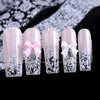 Un set de cinq autocollants pour ongles clairs et roses avec des motifs de dentelle complexes et des nœuds décoratifs.