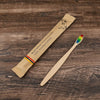 A bamboo toothbrush packaged in natural paper, lying on a wooden surface.