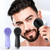 A man is using a black facial cleansing brush on his face, with two brushes visible below.