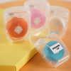 Several clear plastic containers hold spools of pink and orange nylon dental floss.