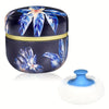 Boîte de poudre de maquillage ronde bleu foncé avec couvercle à motif floral et applicateur en mousse blanche fluffy.
