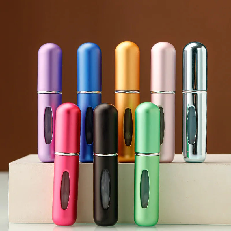 A row of portable refillable perfume bottles in various colors including purple, blue, gold, pink, and silver.