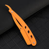 An orange manual straight edge shaver kit with serrated blades rests on a black textured surface.