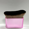 A pink rectangular container holds a black and gold makeup brush for tan and foundation.