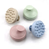 A set of silicone scalp massage and body brushes in pale green, beige, and light blue tones.