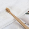 A light wood bamboo toothbrush resting on a white towel.