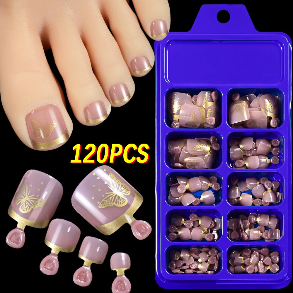 Un juego de 120 uñas postizas con diseño floral lila y dorado mostradas en una mano.