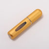 A golden portable refillable perfume bottle with a wooden insert and silver band.