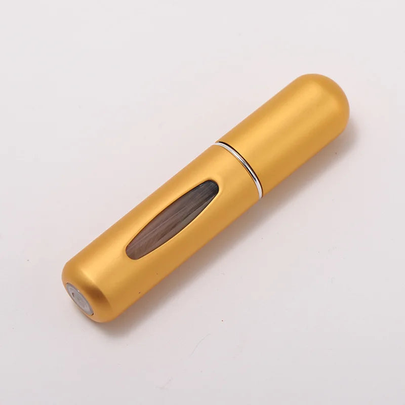 A golden portable refillable perfume bottle with a wooden insert and silver band.