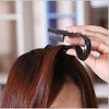 A hand is using a black V-Comb hair styling tool to smooth and finish dark brown hair.