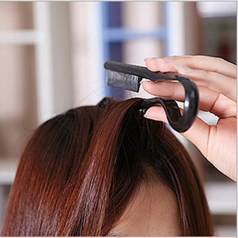 A hand is using a black V-Comb hair styling tool to smooth and finish dark brown hair.