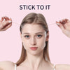 A woman is applying invisible facial lifting tape for contouring to her face.