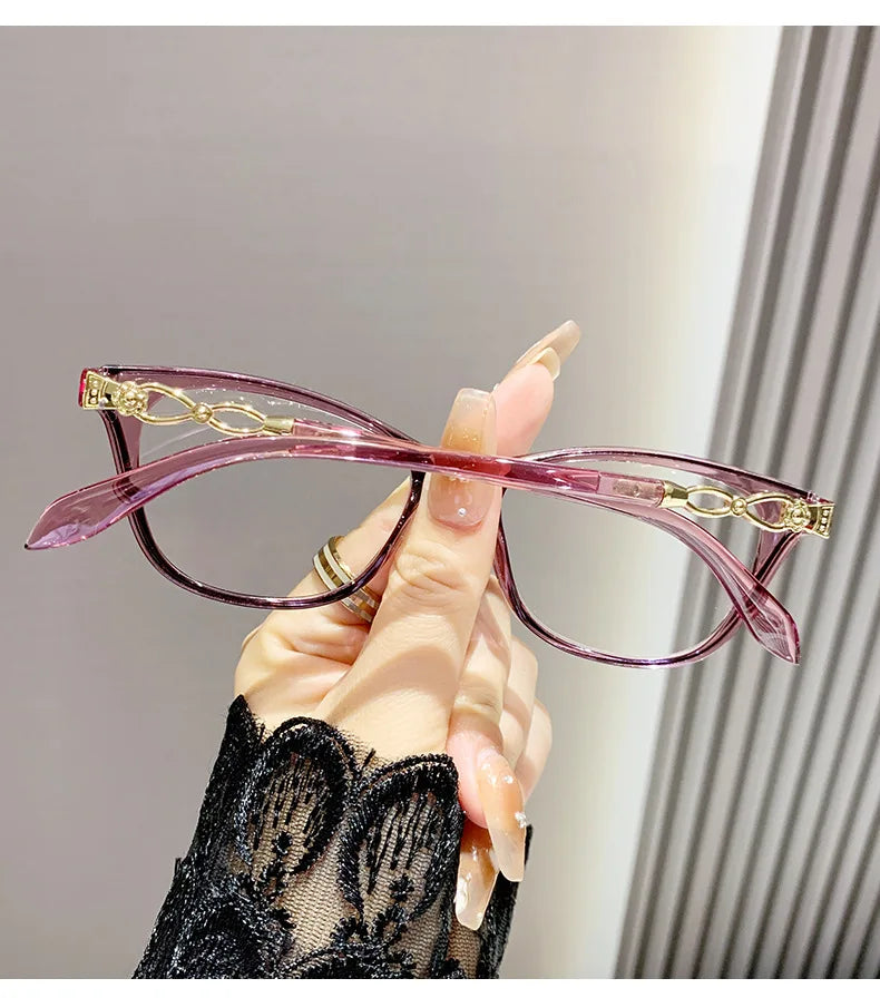 Une main tient des lunettes à œil de chat roses élégantes avec des accents dorés sur un fond clair.