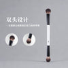 A long, black dual-ended makeup brush with a white handle is shown next to circular views of the brush heads.