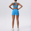 Una mujer modela un conjunto deportivo de yoga y gimnasio azul brillante, transpirable y de secado rápido, con top y shorts.
