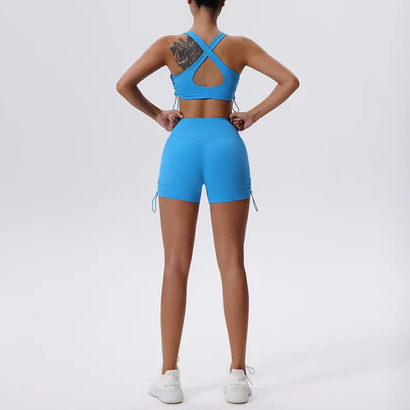 Una mujer modela un conjunto deportivo de yoga y gimnasio azul brillante, transpirable y de secado rápido, con top y shorts.