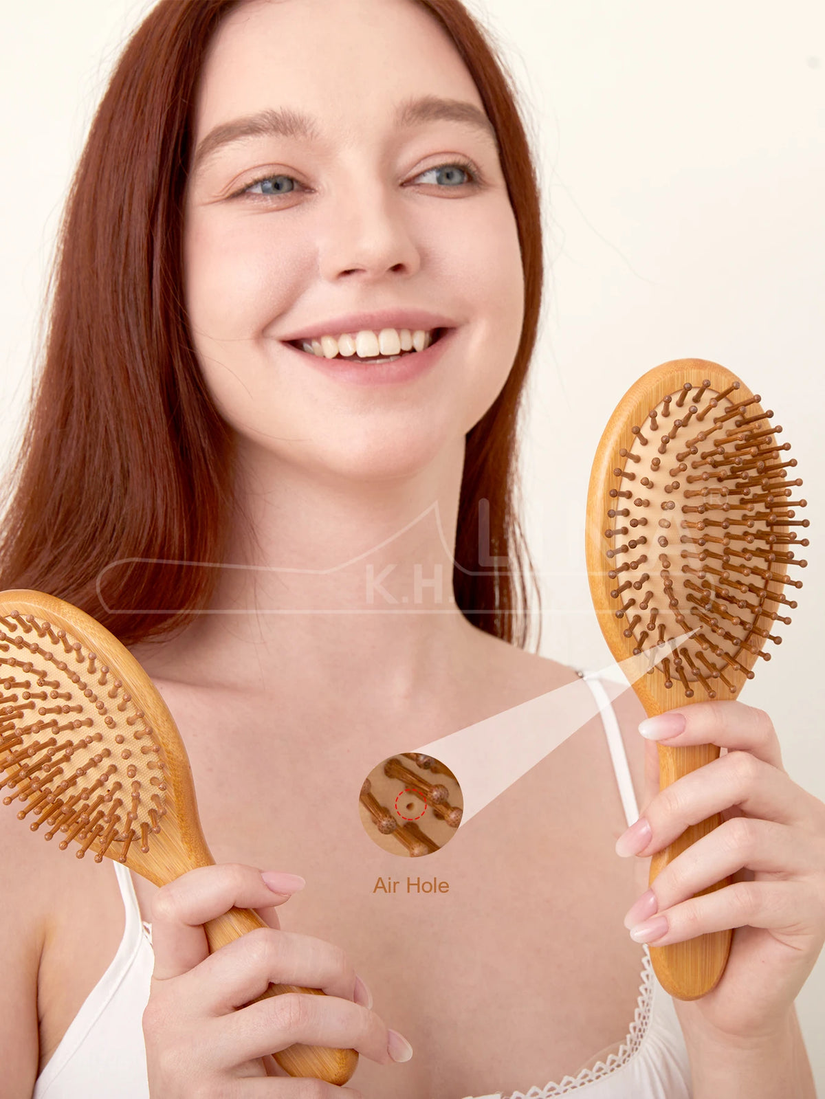 A woman holds a wooden bamboo hair brush with an air hole, demonstrating the product for gentle detangling.