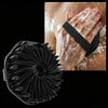 Un cepillo exfoliante de silicona negra junto a una mano siendo exfoliada con un exfoliante corporal de silicona natural.