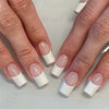 A set of white French style coffin shape press-on nails displayed on fingers.