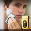 A man is using a gold-colored electric foil shaver on his face.