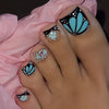 A hand displaying various press-on fake nails featuring a black and turquoise floral design.