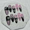 A set of glitter diamond press on nails featuring black, pink, and zebra print designs displayed on a white surface.
